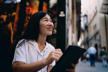 Woman looking up from tablet with peaceful smile, reflecting creative confidence and harmony between digital tools and imaginative thought process.