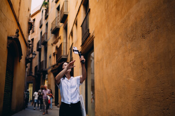 Asian woman records video with smartphone on gimbal, exploring urban space through lens, reflecting digital storytelling, mobile autonomy and creative exploration.
