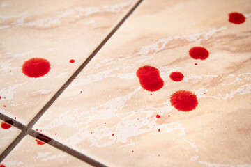 Real fresh red blood drops on bathroom tile floor indoors at home. Injury or crime concept.