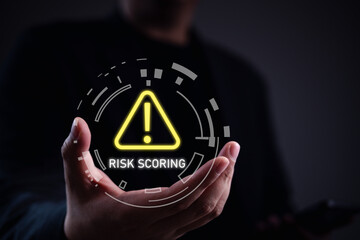 Risk scoring alert concept. Businessman holding glowing warning icon in digital interface, illustrating data-driven risk evaluation, cybersecurity analysis, and threat monitoring system.