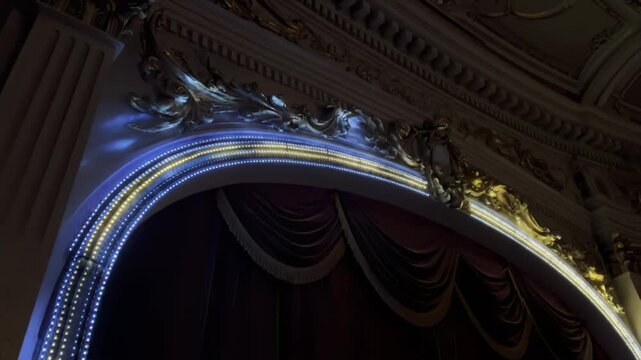 Ornate opera house proscenium arch illuminated by modern stage lights