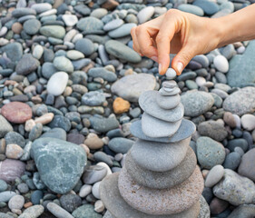 Woman making cairn on the beach. Activity