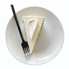 A piece of cake with white cream is on a plate. Isolated on a white background.