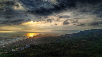 aerial landscape of sunset between the beach and green forest