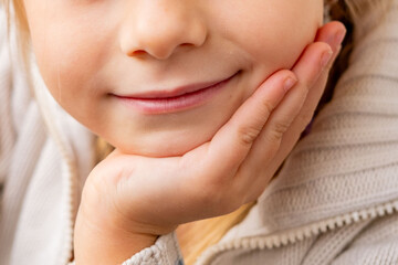 Sweet little 6-year-old girl with shy smile, preschooler resting chin on hand, childhood joy and...
