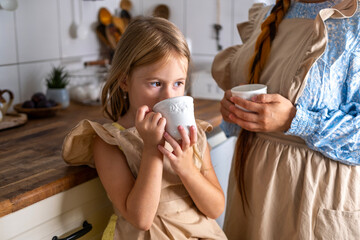 cute child, blonde girl, Long-haired mother and daughter tea party together in kitchen, home and relaxation, serenity domestic life