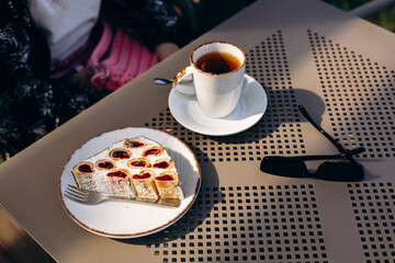 Slice of berry cake and coffee on cafe terrace table in the morning.
