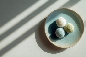 Japanese mochi cakes, a sweet dessert, presented on a minimalist ceramic plate with aesthetic sunlight and strong shadows