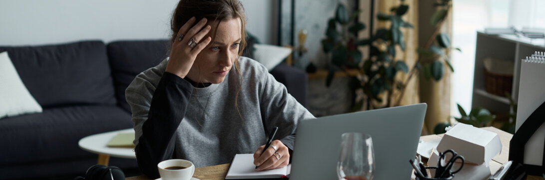 Young woman struggles with feelings of depression while working from home in her cozy living space