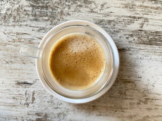 Cup of coffee with foam on wooden table. Coffee break.  Top view. 