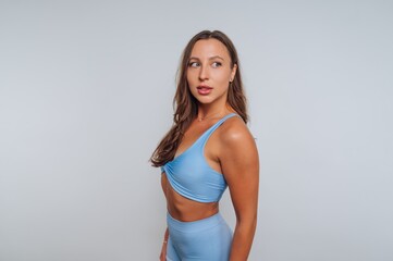Fototapeta premium Woman in light blue activewear posing against a plain backdrop during a fitness photoshoot