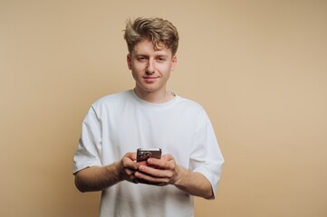 Young man using smartphone against a simple background while engaging in casual activity