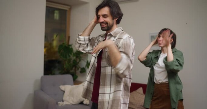 Guy and a girl dance a synchronized dance and prepare for a flash mob at home in a cozy apartment. Fun flash mob and synchronized dance preparation at cozy home