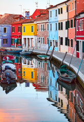 Murano island in Venice, Italy. Motorboats parked along the channel with Colorful houses. Venezia evening sunset view at street old European fisherman village.