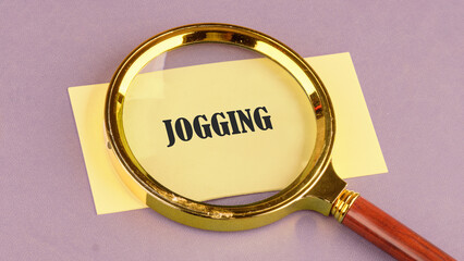 Fitness, healthy and active lifestyles concept. JOGGING word through a magnifying glass on a yellow sticker, it symbolizes the importance of a healthy lifestyle.