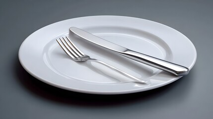 Simple, elegant place setting with a white ceramic plate, silver fork and knife placed on a plain gray background, creating a minimalist and sophisticated dining scene.