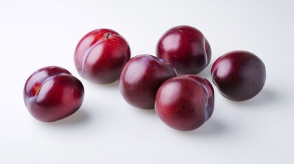 Fresh ripe plums arranged in a minimal still life setting on a clean white surface for artistic display