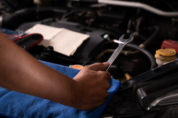 Young man fixing car engine by himself at home, concept of DIY repair, maintenance, and saving money on vehicle service.