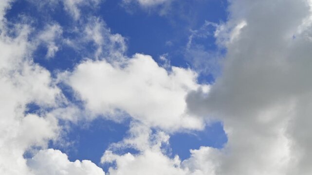 White fluffy clouds crossing the blue sky from left to right in timelapse. Fair-weather cumulus clouds. Dreamlike skyscape. Seamless looping version of the clip.
