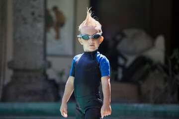 Happy child in wetsuit and goggles learn to swim, have fun at poolside in swimming pool. Healthy family lifestyle, little kids water sports activity, swimming lessons with parents at training class