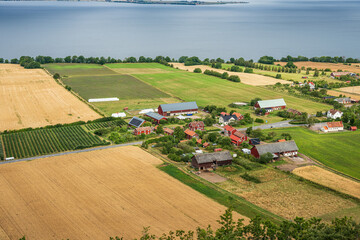 Vast farmland landscape with lake and cloudy sky.