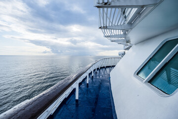 Passenger ferry bow deck with ocean horizon under cloudy sky.