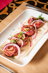 Juicy meat rolls garnished with onions and herbs for a rich culinary experience