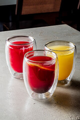 Three vibrant beverages sit on a smooth table, each bursting with color and flavor