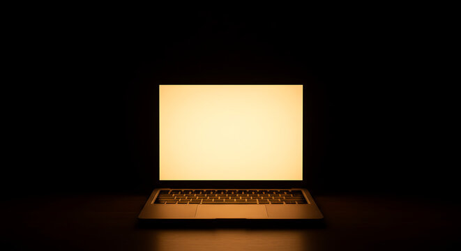 A laptop with a bright, glowing, warm white screen is centered in darkness, with the light intensely illuminating the keyboard and reflecting slightly on the surface