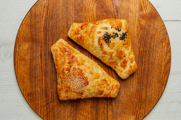 Freshly baked pastries topped with sesame and black seeds, served on a rustic wooden board