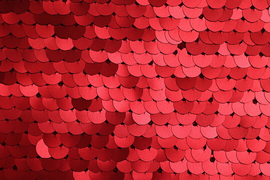 Close-up of matte finish spangle fabric in metallic red tones, showcasing layered sequins with subtle shine and textured surface, ideal for fashion and textile design.