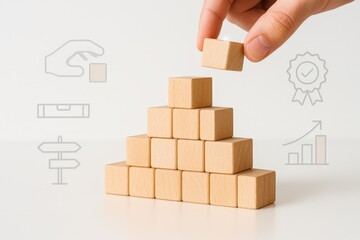 Human hand placing a wooden cube on a pyramid structure made of other wooden blocks, representing concepts such as building, progress, and development against a clean, minimalist background, with...