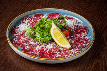Savor tender beef carpaccio topped with herbs, cheese, and lemon, arranged artistically on a plate