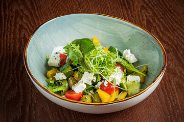 A vibrant salad with diced tomatoes, peppers, greens, and crumbled cheese