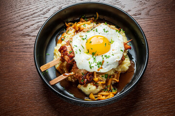 A delicious meal features creamy mashed potatoes topped with a fried egg and savory sauce