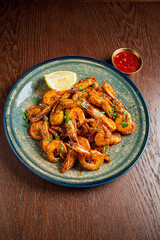 A delicious plate of shrimp is accompanied by a tangy lime slice and red sauce