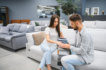Obraz premium Young couple choosing sofa fabric in furniture store