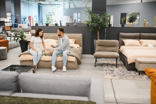 Couple choosing bed furniture in modern store showroom