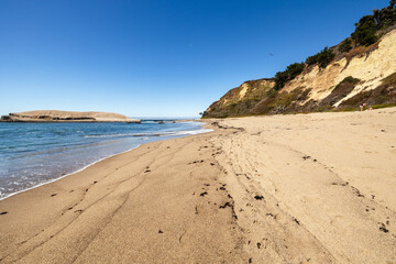 Greyhound Rock Beach in Santa Cruz County, California USA. Scenic sandy shoreline with ocean waves, dramatic coastal cliffs, and Greyhound Rock island creating a peaceful and natural Pacific Coast