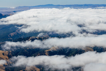 Scenic view from Mount Tamalpais East Peak in Marin County, California, with rolling hills, oak woodlands, and low clouds drifting through the valleys on a clear summer day