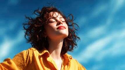 A joyful woman with curly hair enjoys the sunshine, showcasing her carefree spirit against a vibrant blue sky, embodying happiness and freedom in the moment.