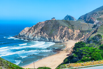 Scenic view of Highway 1 coastline from Gray Whale Cove Trail near Pacifica, California, with ocean waves, rugged cliffs, and lush green hills along the Pacific coast