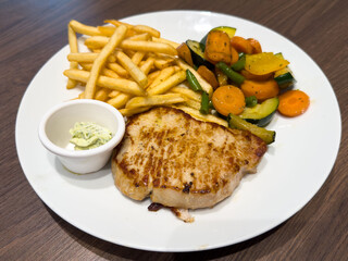 Delicious grilled chicken steak with french fries and mixed vegetables on a plate