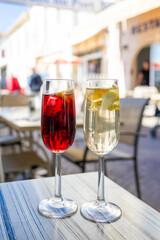Two glasses of refreshing sangria cocktails on outdoor terrace table, red and white versions with fruit, perfect summer drinks in Mediterranean setting