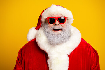 Smiling Santa Claus in a bright red suit wearing trendy sunglass against yellow background celebrating Christmas