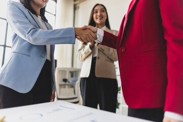 Businesswoman shaking hands with colleague after meeting in office. Business people shaking hands in the office for a deal, collaboration. Employees with handshake for welcome or greeting.