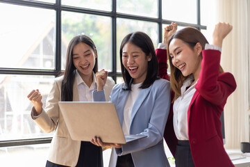 Group of female co-workers looked at the laptop screen, their expressions of excitement and surprise. group of young businesswomen who are successful in their startup businesses.