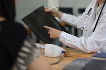 Doctor measuring blood pressure of patient during medical examination. Doctor is discussing x ray result while taking a patient blood pressure during medical examination in examination room hospital.