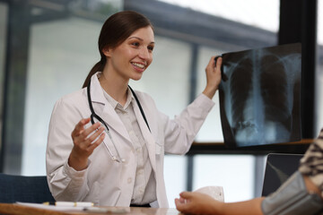 Doctor measuring blood pressure of patient during medical examination. Doctor is discussing x ray result while taking a patient blood pressure during medical examination in examination room hospital.