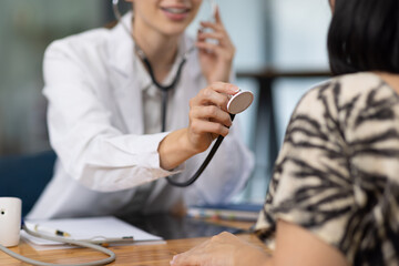 Doctor examining patient using stethoscope in hospital office. Female doctor listens to a patient's heartbeat with stethoscope during medical exam. She focuses on heart and lung health, care expertise